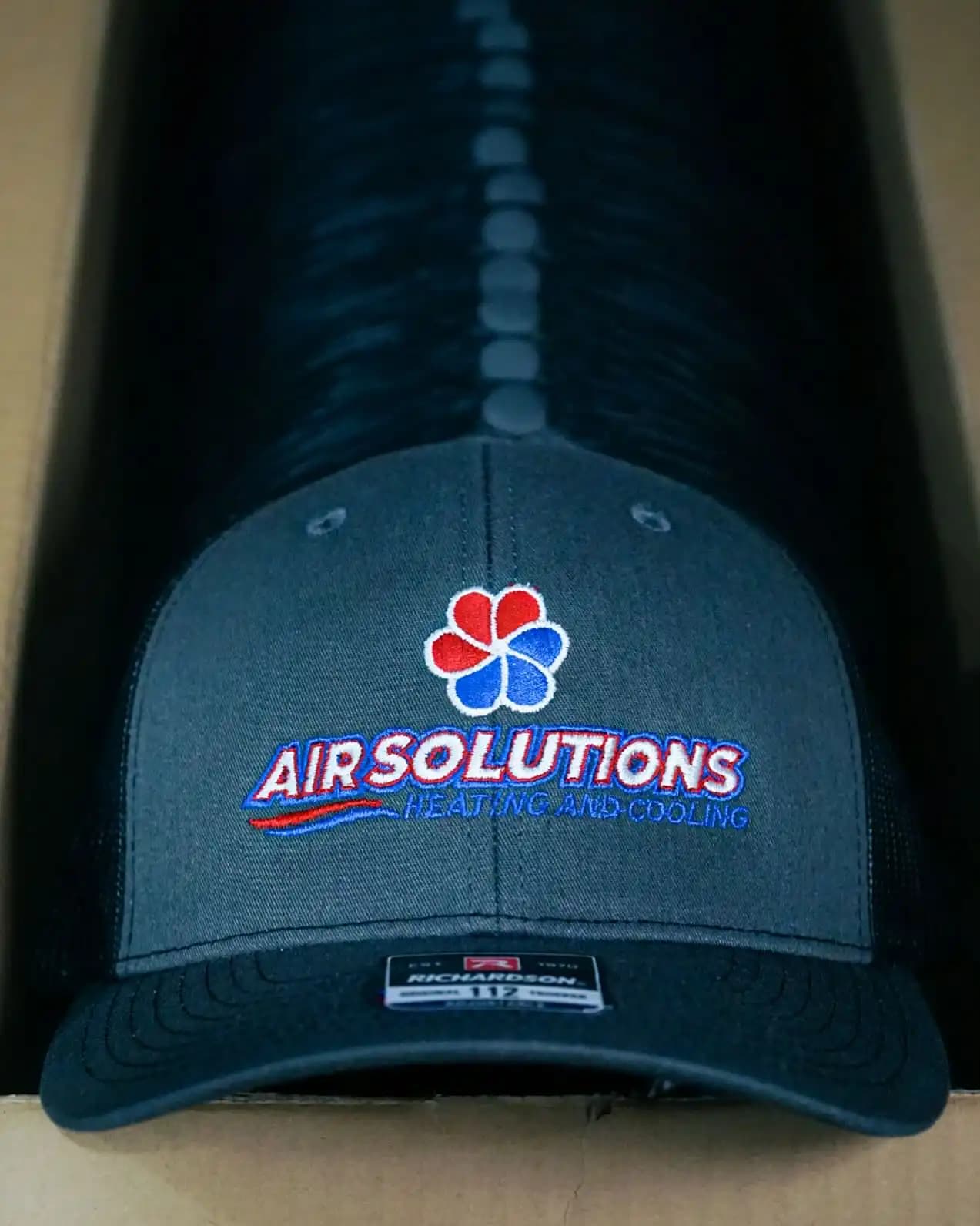 Air Solutions Heating and Cooling HVAC logo on Richardson 112 caps, demonstrating 100% manual digitizing for high-speed commercial embroidery production.