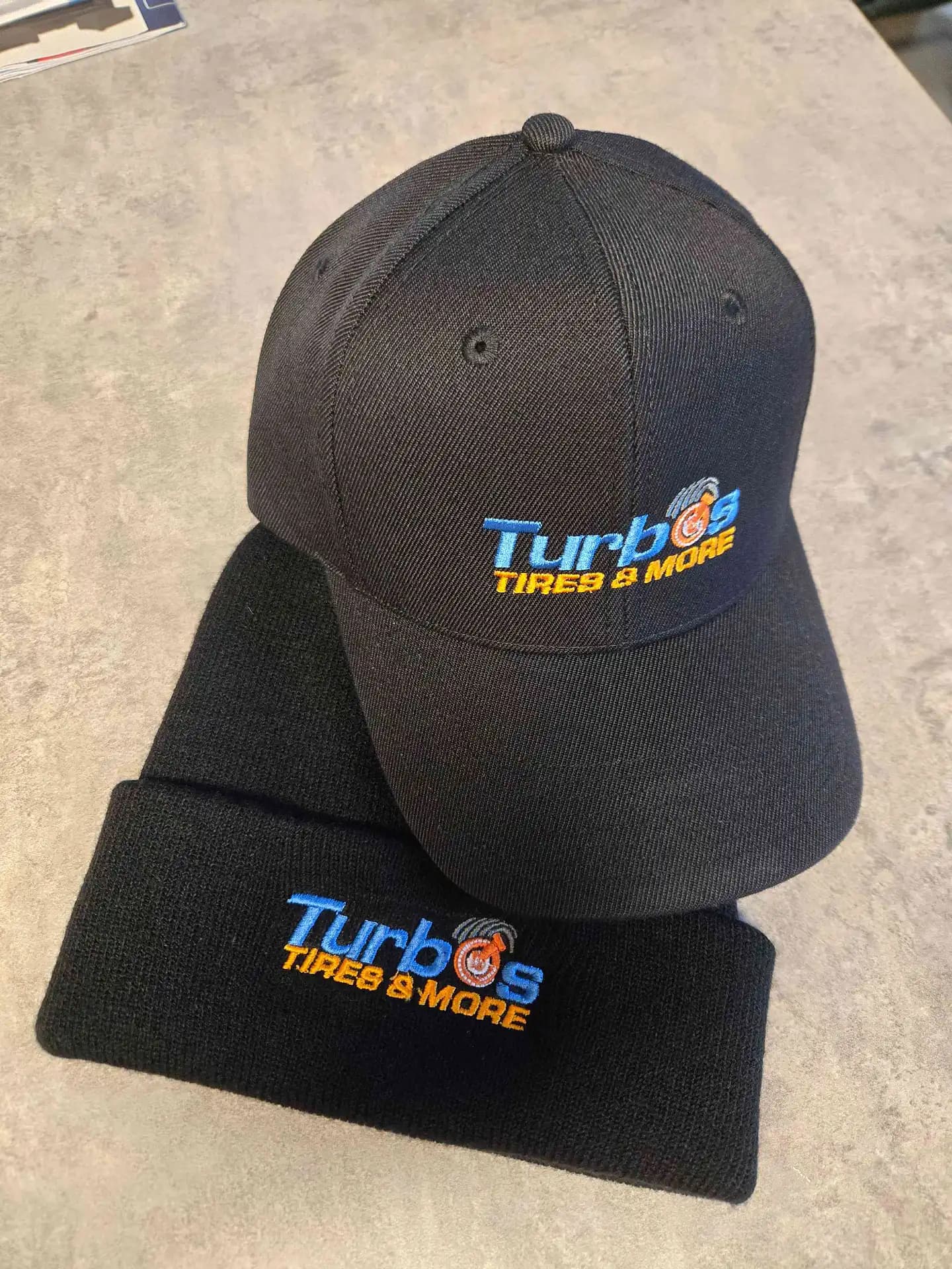 Turbo’s Tires & More automotive logo on structured caps and beanies, featuring 100% manual digitizing by Sassy Digitizing for a rugged, professional look.